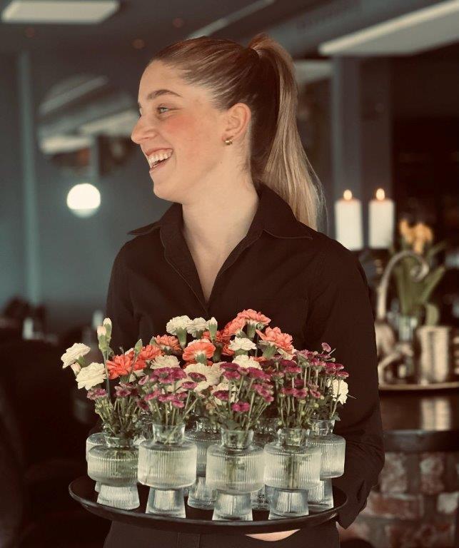 Servitør på restaurant vadskjæret, som bærer en fin bukett til kundene.